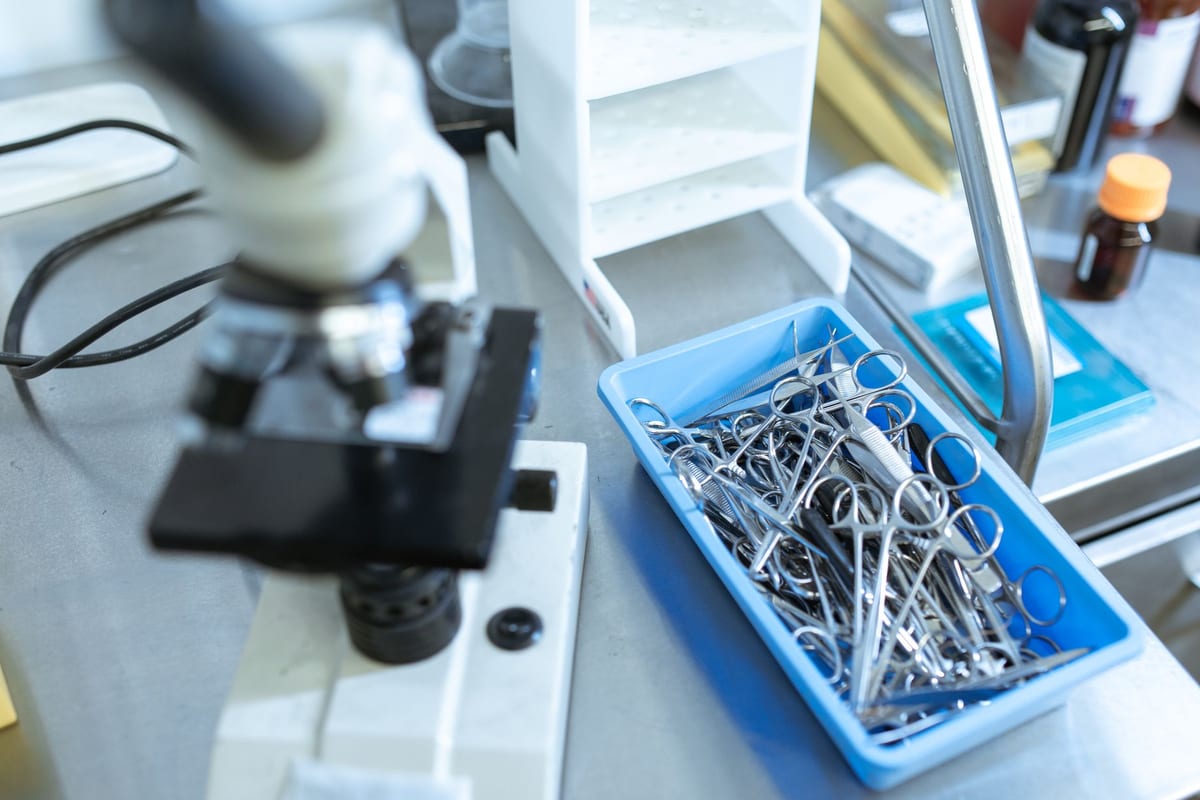 A microscope and a tray of surgical instruments on a lab bench